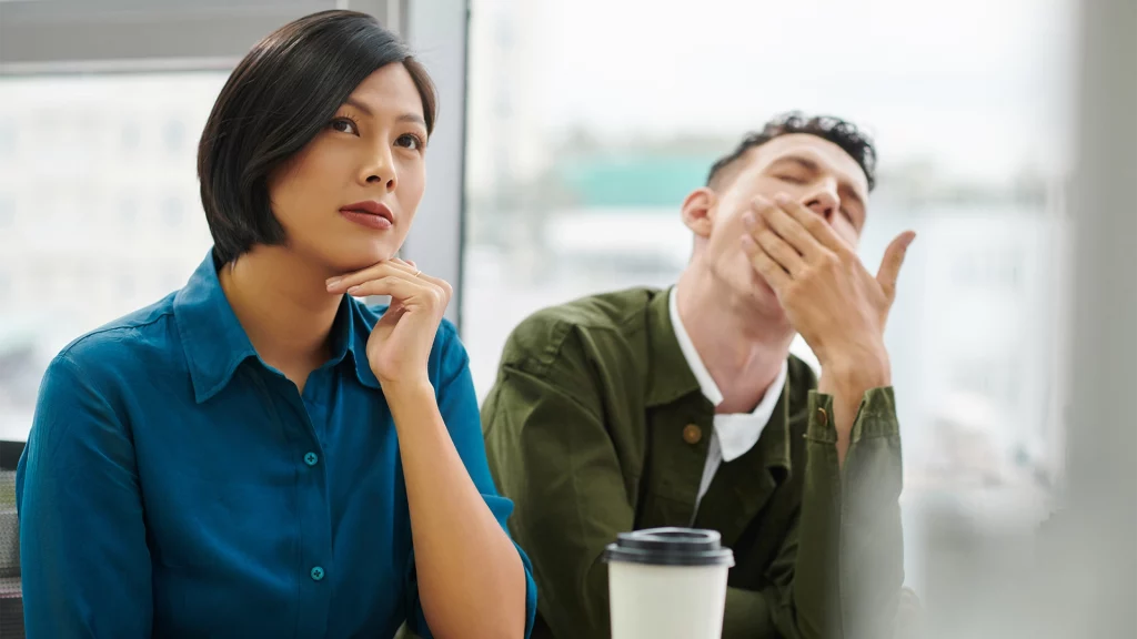 Imagén de dos personas aburridas y en silencio durante una reunión de trabajo